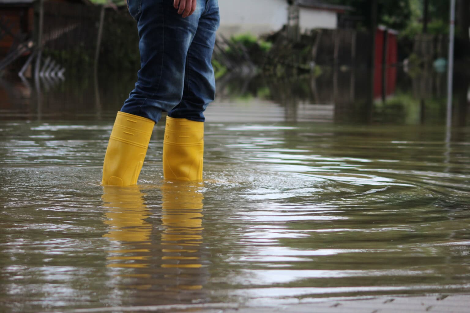 Ein Mensch in gummistiefeln steht im Hochwasser.